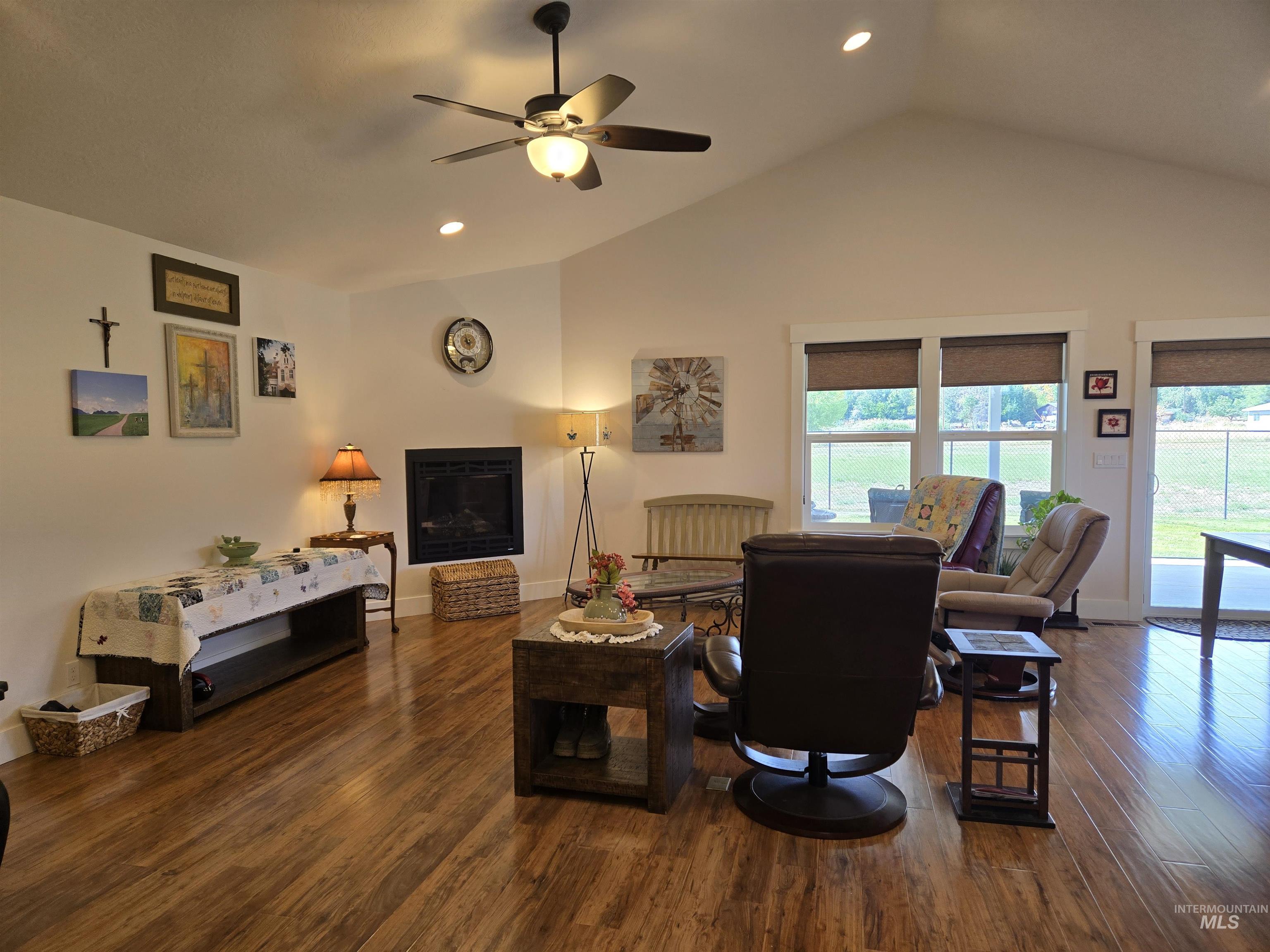 Living room with recessed lighting, dark wood-style floors, a glass covered fireplace, high vaulted ceiling, and a ceiling fan