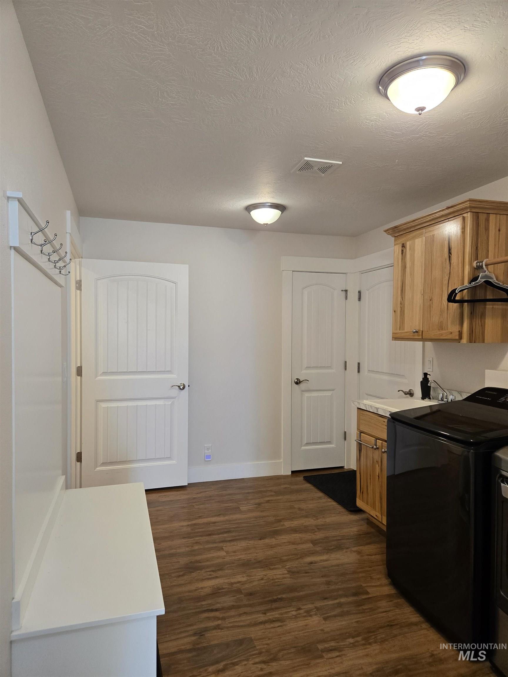 Kitchen featuring light countertops, a textured ceiling, dark wood-style floors, and washing machine and clothes dryer