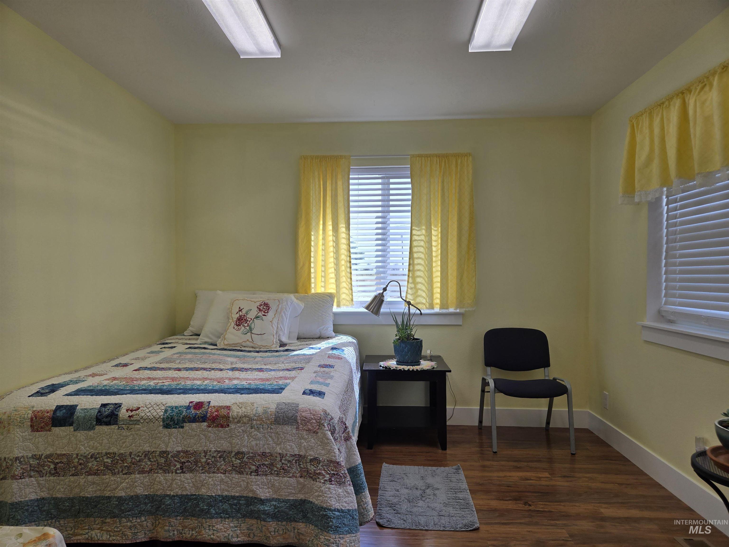 Bedroom featuring dark wood-style floors and baseboards