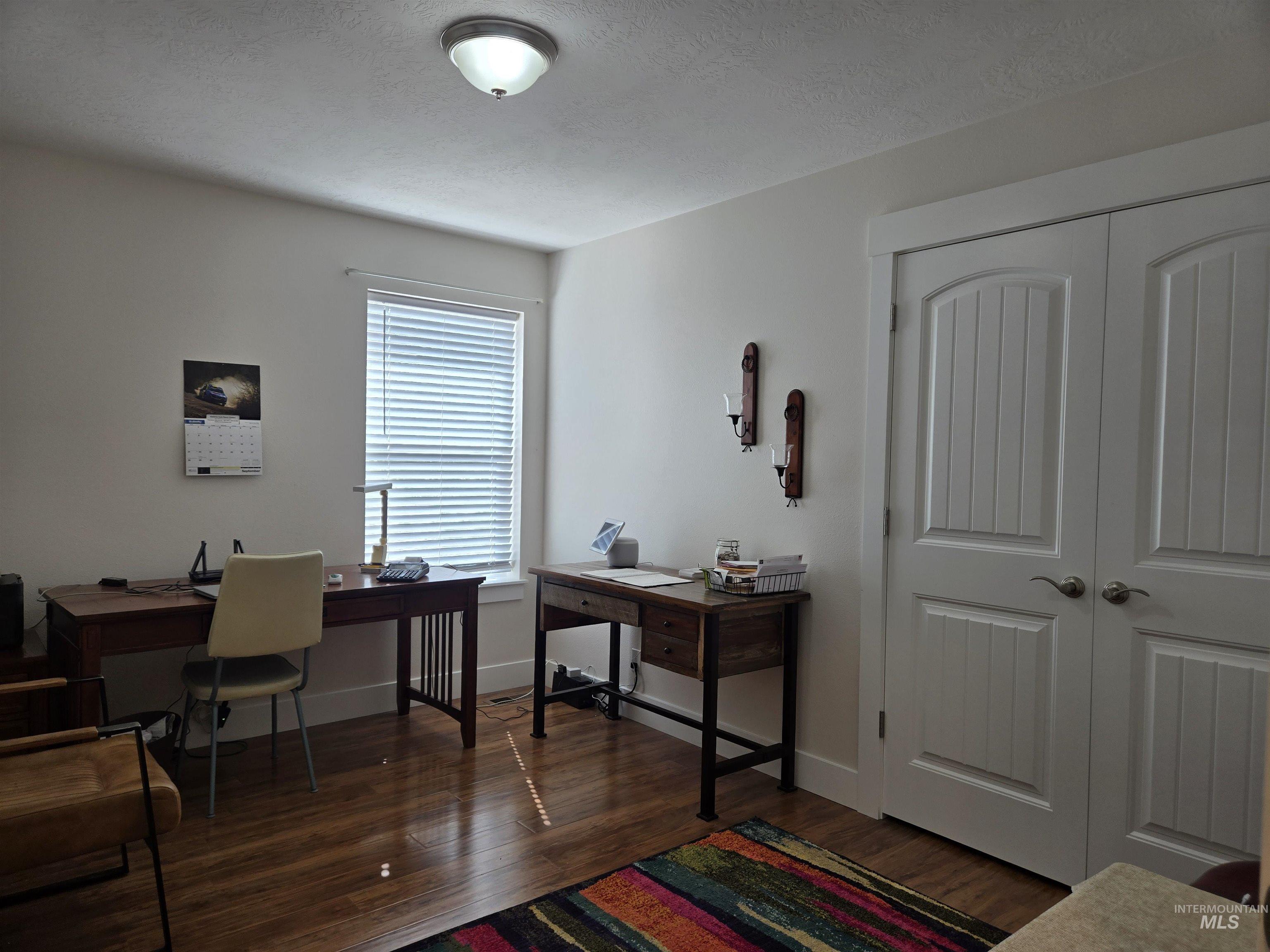 Bedroom being used as a Home office with dark wood-style floors and a textured ceiling