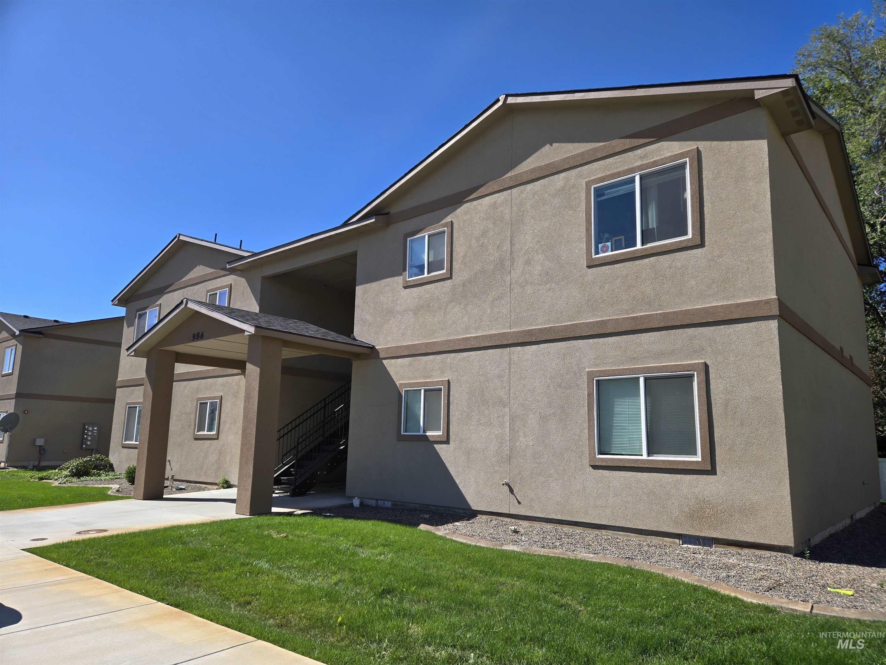 View of front of house with stucco siding, a front yard, and stairway