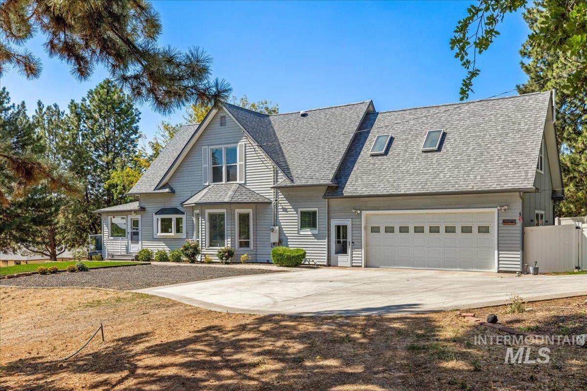 View of front facade with concrete driveway and a shingled roof
