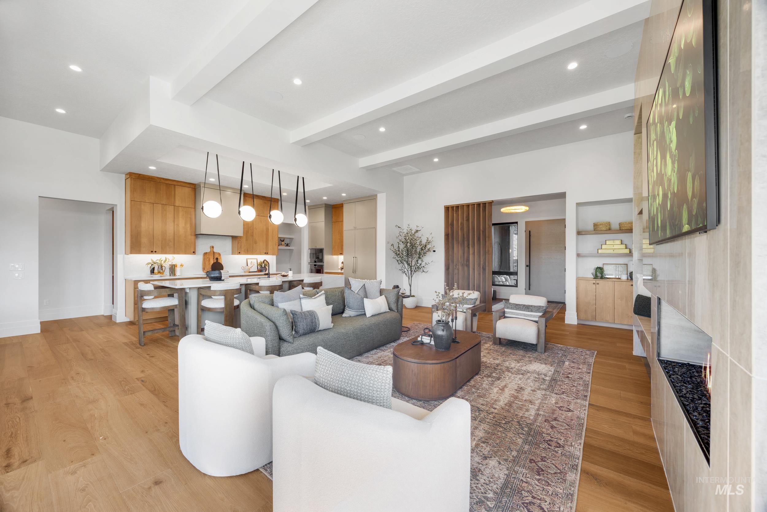 Living area with beam ceiling, light wood-style flooring, recessed lighting, and a fireplace