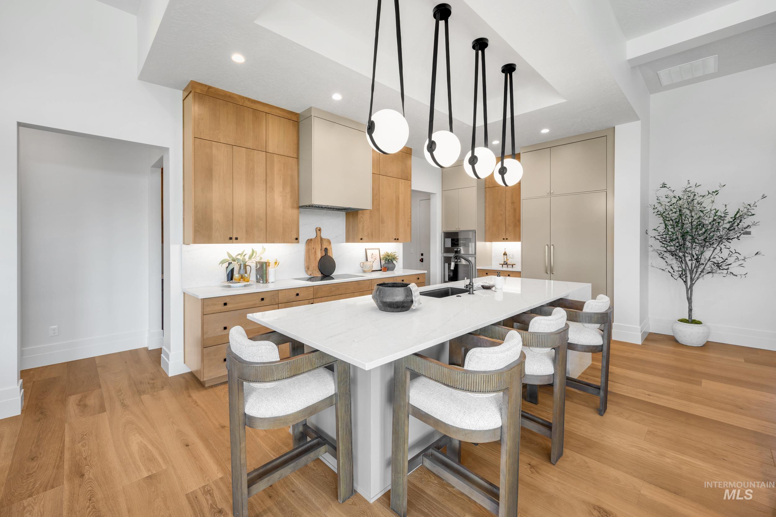 Kitchen with pendant lighting, a kitchen breakfast bar, light stone countertops, light wood-style floors, and recessed lighting