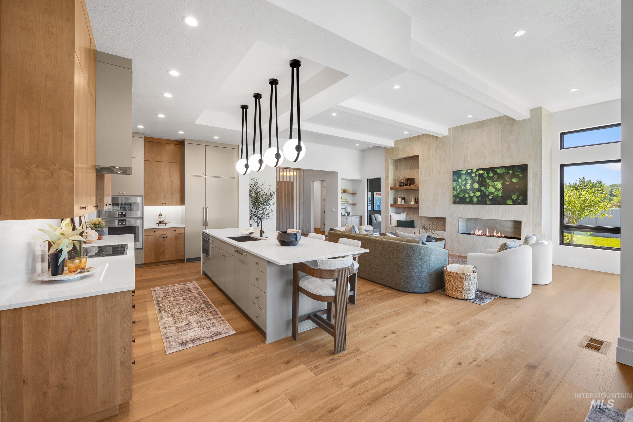 Kitchen featuring beamed ceiling, a kitchen breakfast bar, decorative light fixtures, an island with sink, and open floor plan