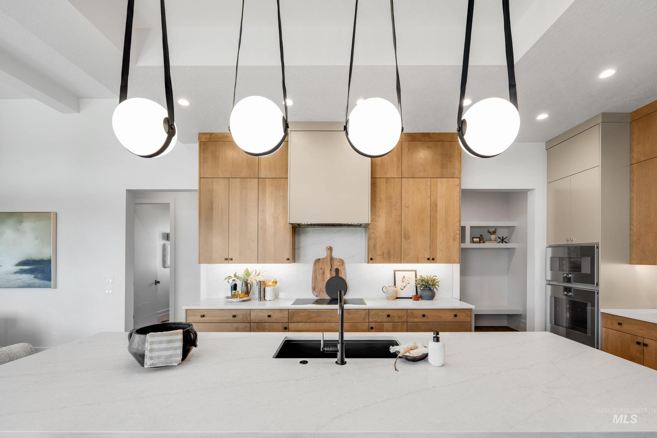 Kitchen with a large island, light stone countertops, hanging light fixtures, decorative backsplash, and recessed lighting