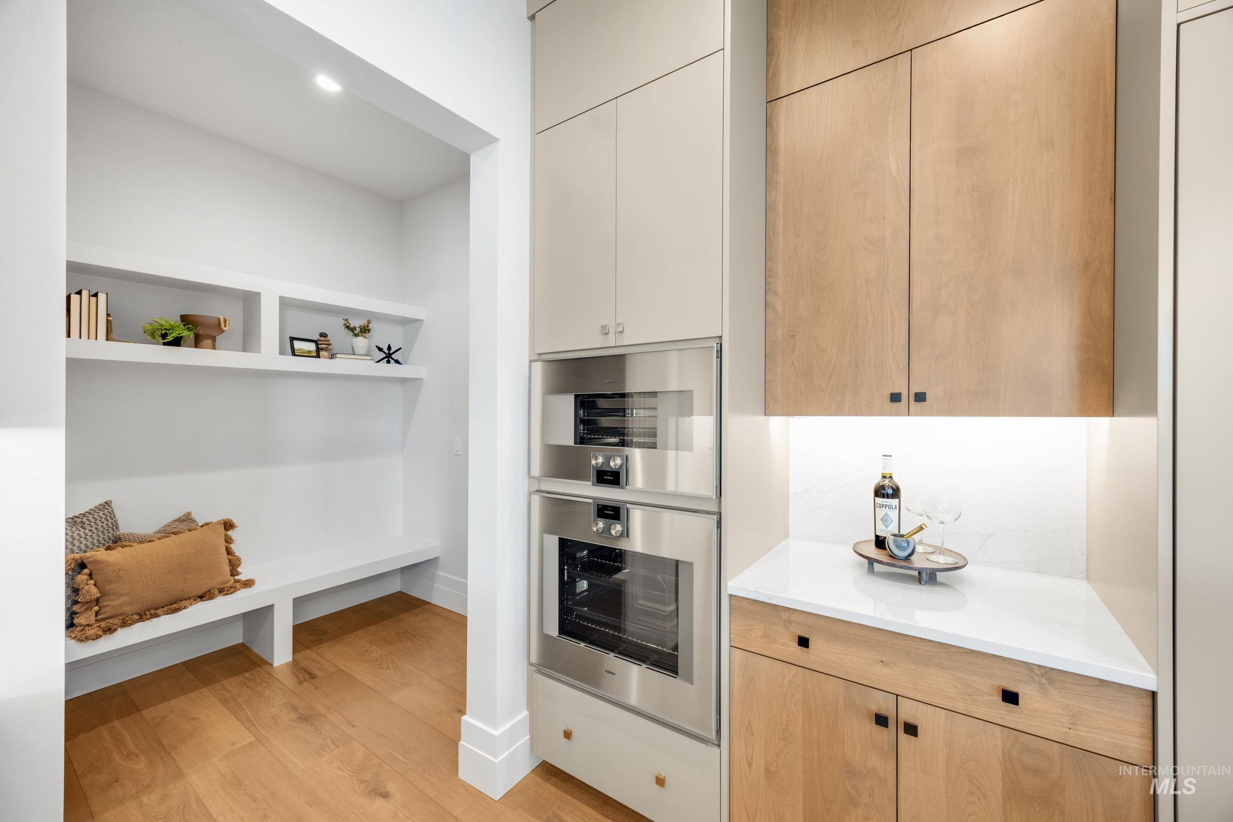 Kitchen featuring light wood-style floors, light stone countertops, light brown cabinetry, and stainless steel double oven