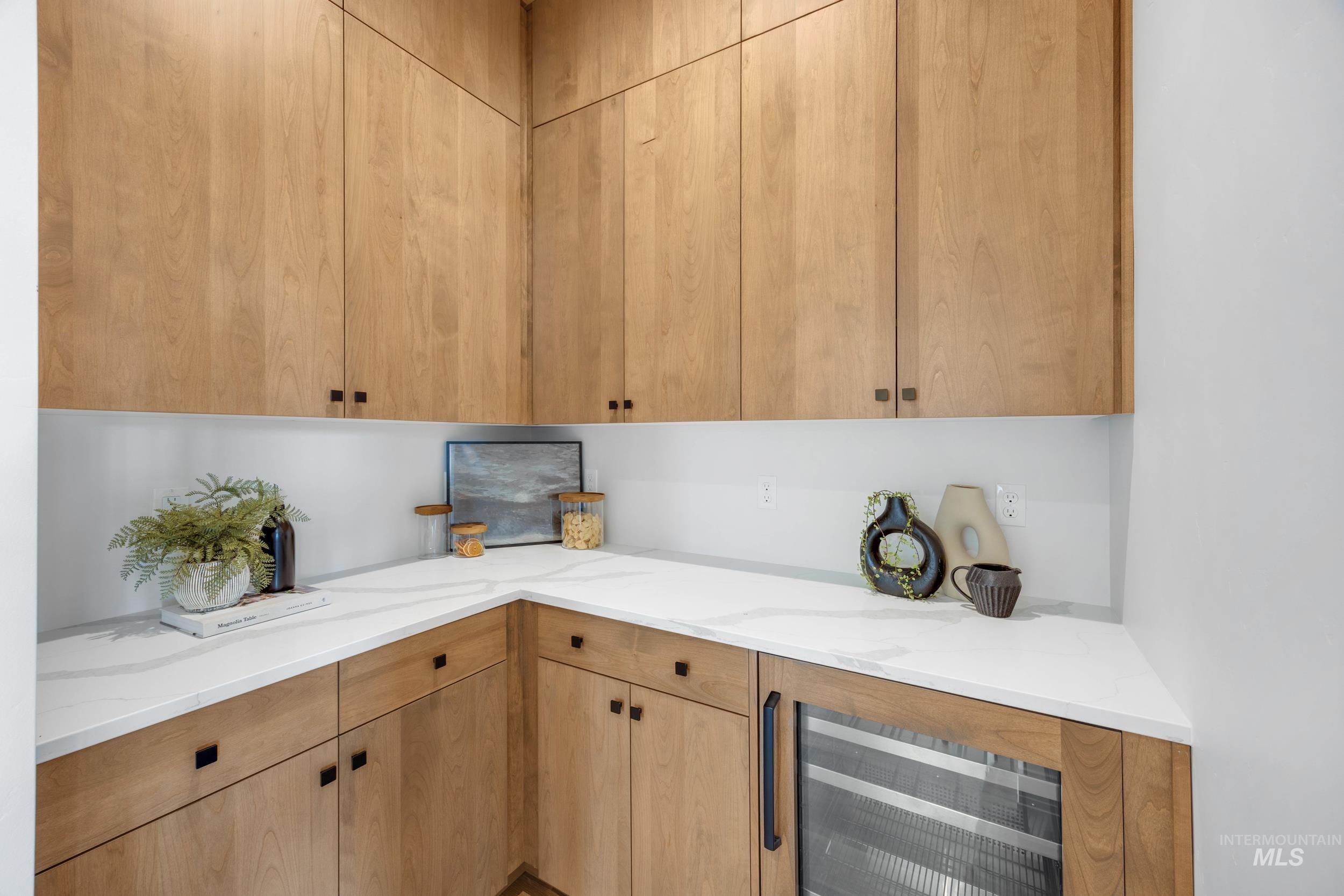 Kitchen with beverage cooler and light stone counters