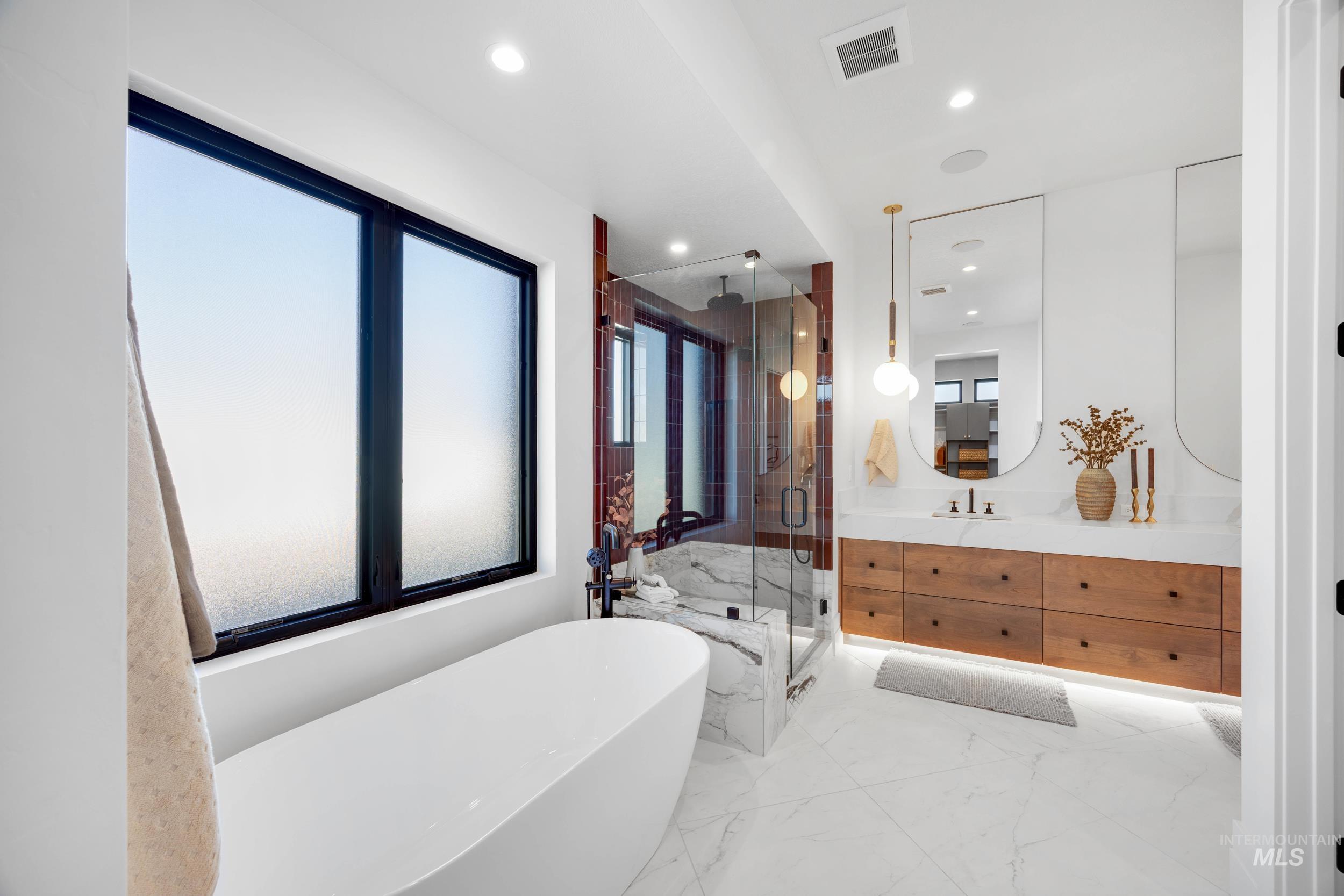 Bathroom with vanity, a freestanding tub, a marble finish shower, marble tiled floors, and recessed lighting