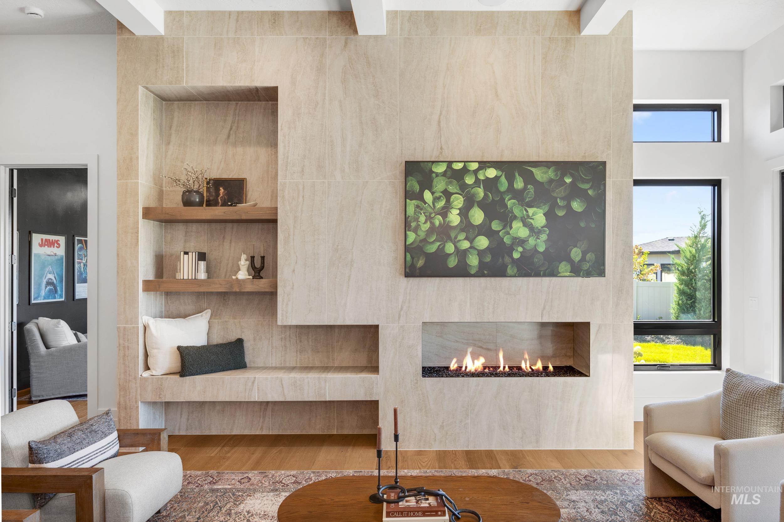 Living area featuring wood finished floors, a lit fireplace, and beam ceiling