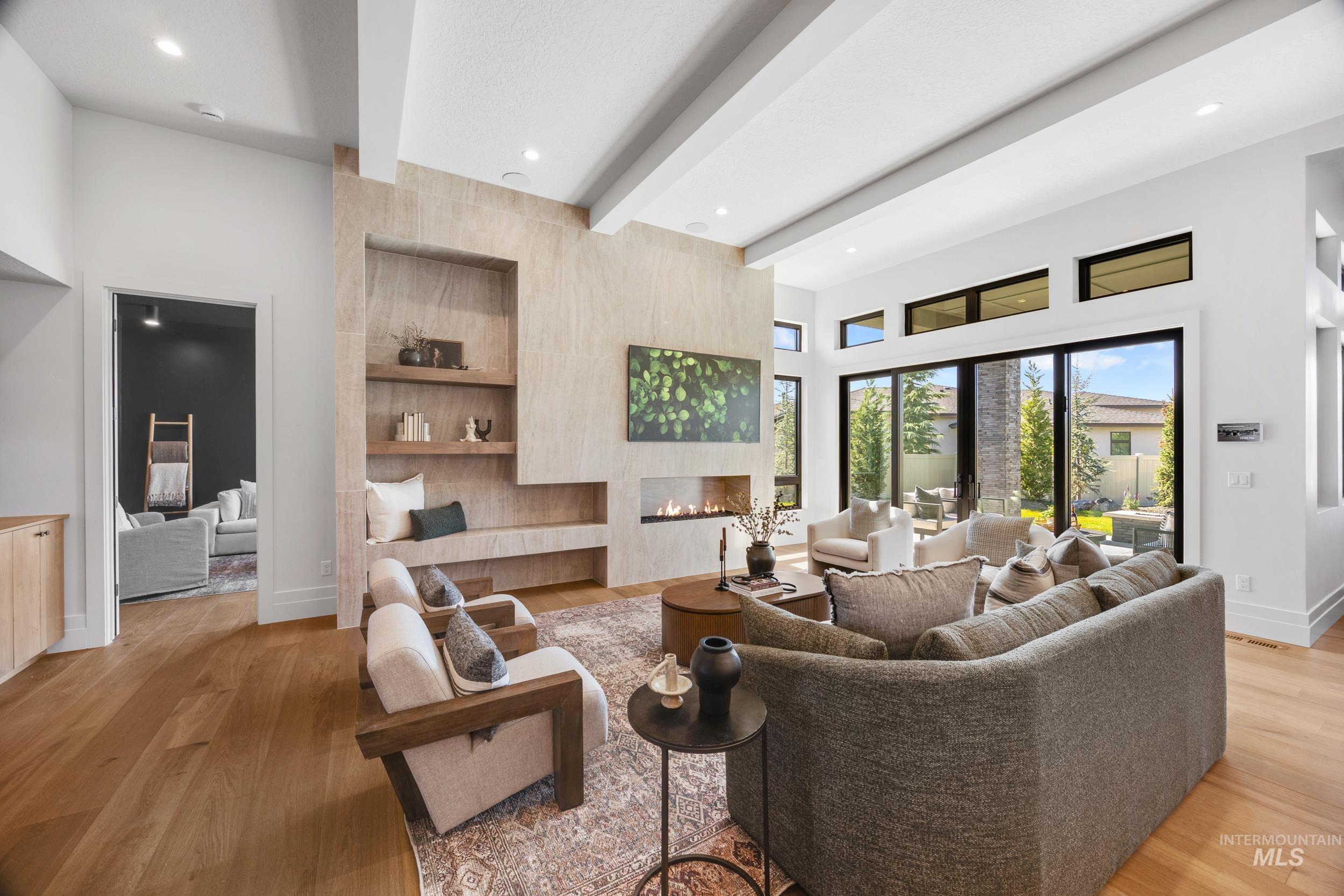 Living room with beamed ceiling, a tiled fireplace, light wood-type flooring, and recessed lighting
