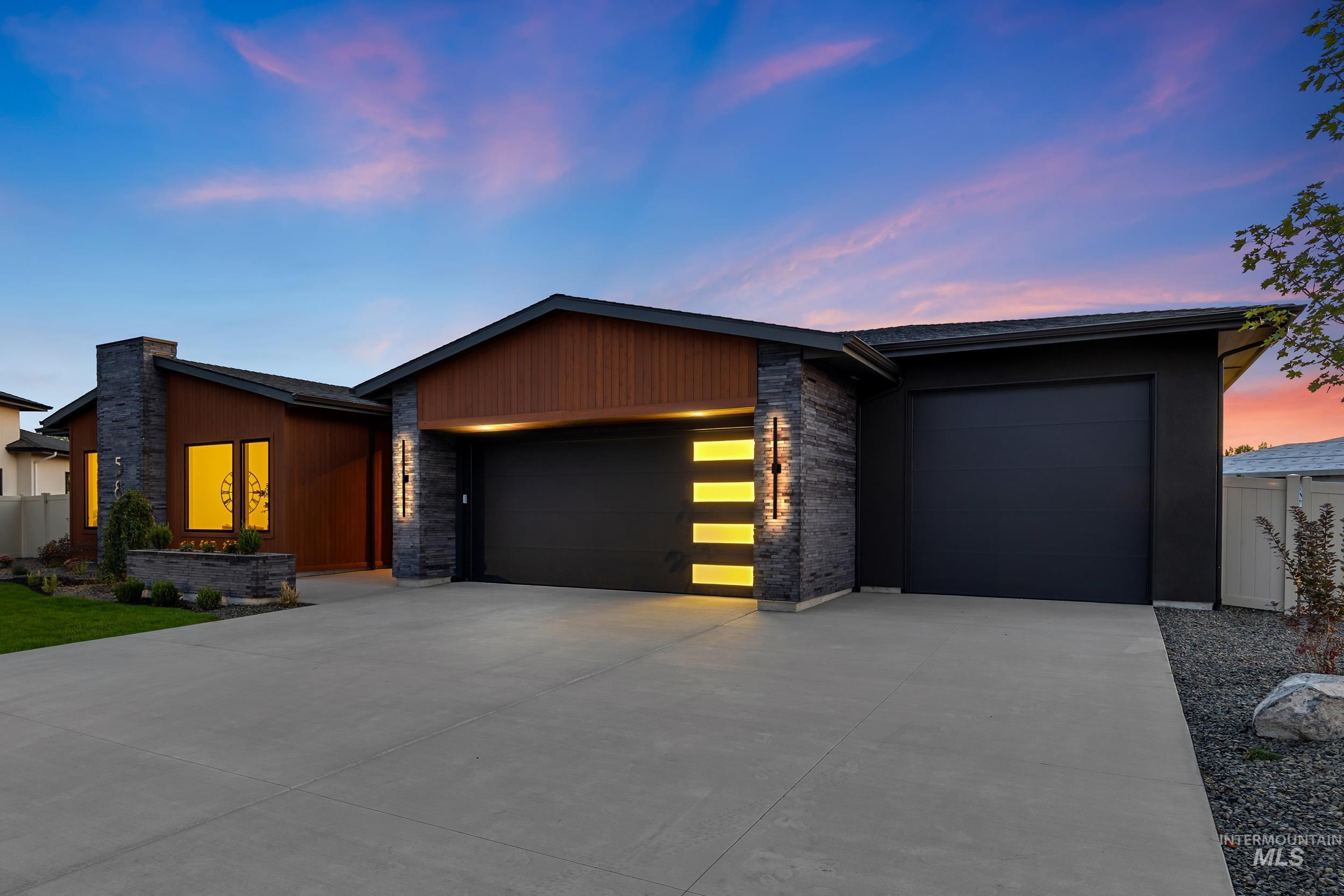 View of front of property with stone siding, an attached garage, and concrete driveway