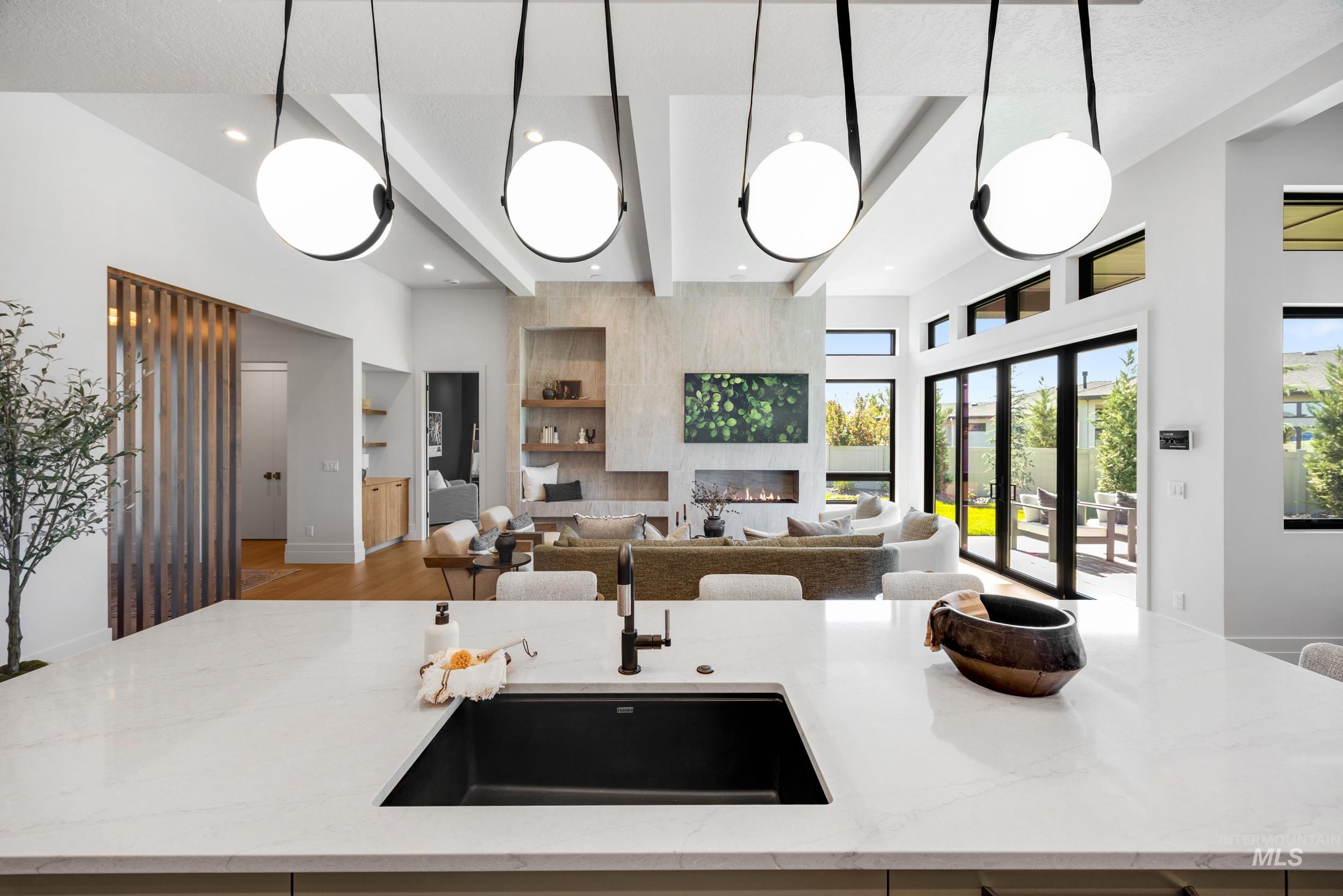 Kitchen featuring an island with sink, light stone countertops, pendant lighting, open floor plan, and a high ceiling