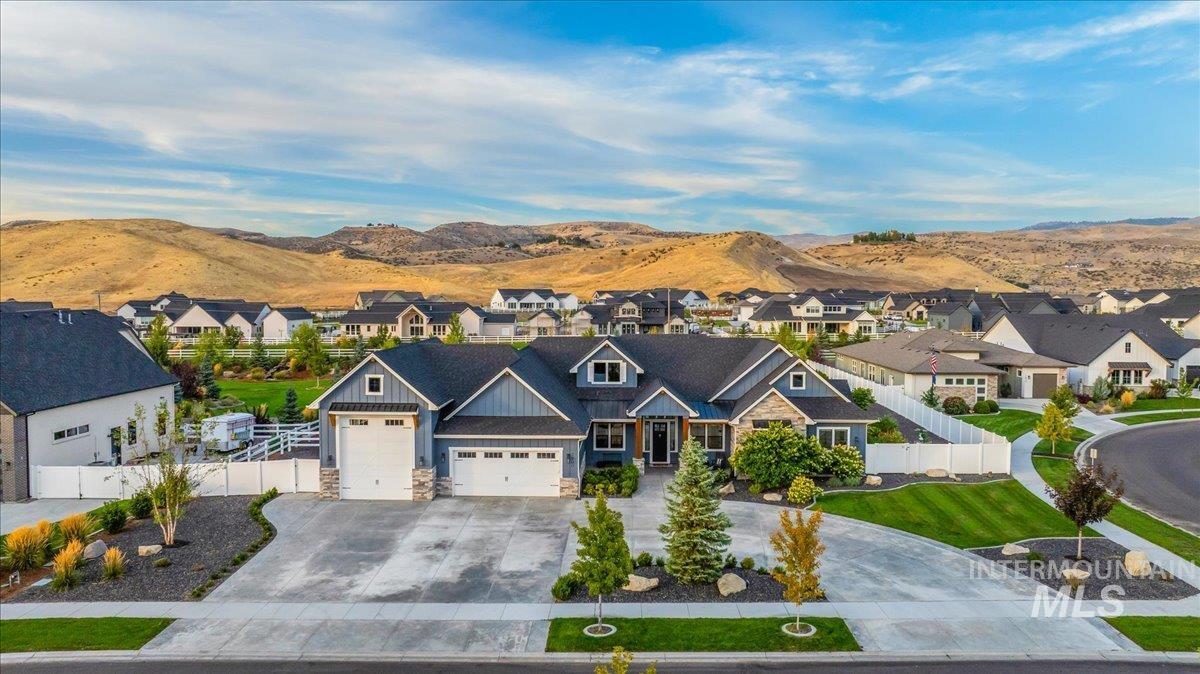 View of front facade featuring a mountain view, stone siding, driveway, an attached garage, and a residential view