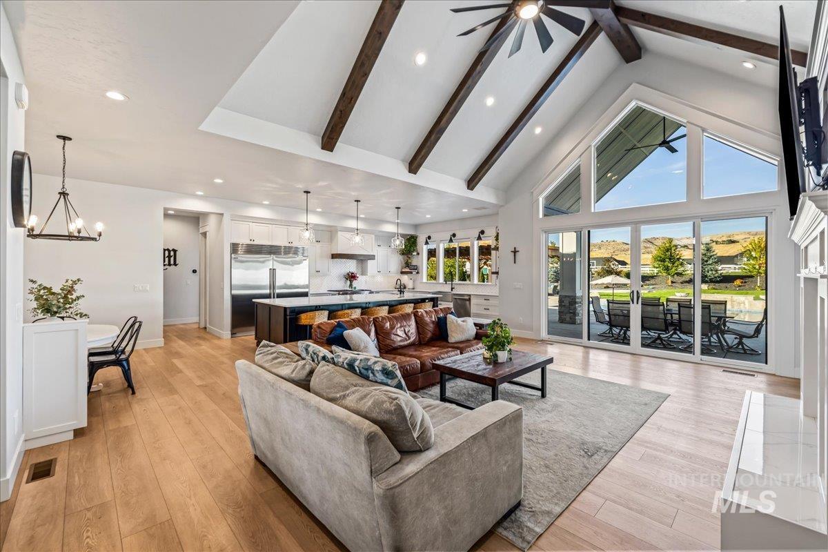 Living area with high vaulted ceiling, beam ceiling, a ceiling fan, light wood finished floors, and recessed lighting