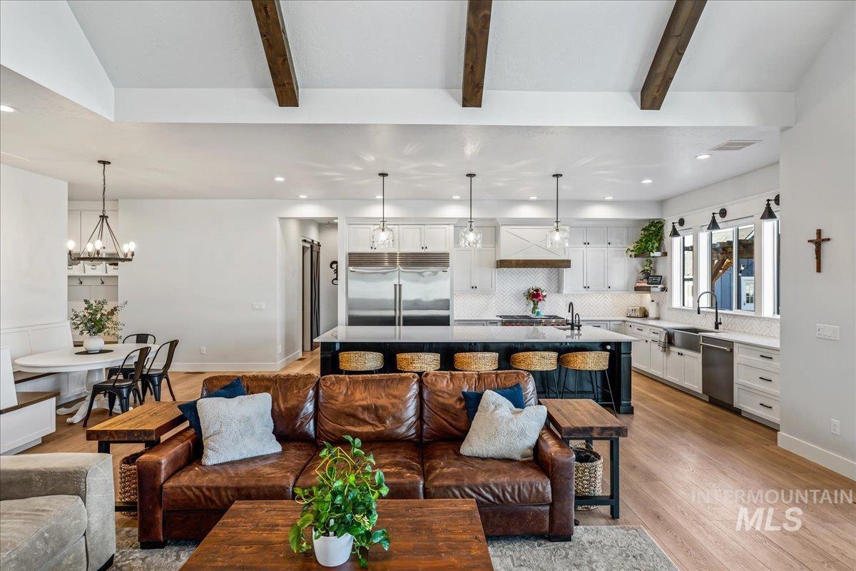 Living area with light wood-type flooring, recessed lighting, a chandelier, and beam ceiling