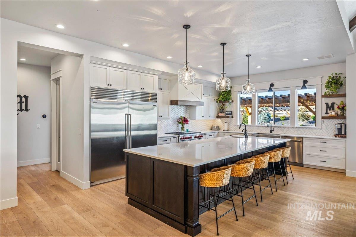 Kitchen with white cabinets, appliances with stainless steel finishes, decorative backsplash, open shelves, and recessed lighting