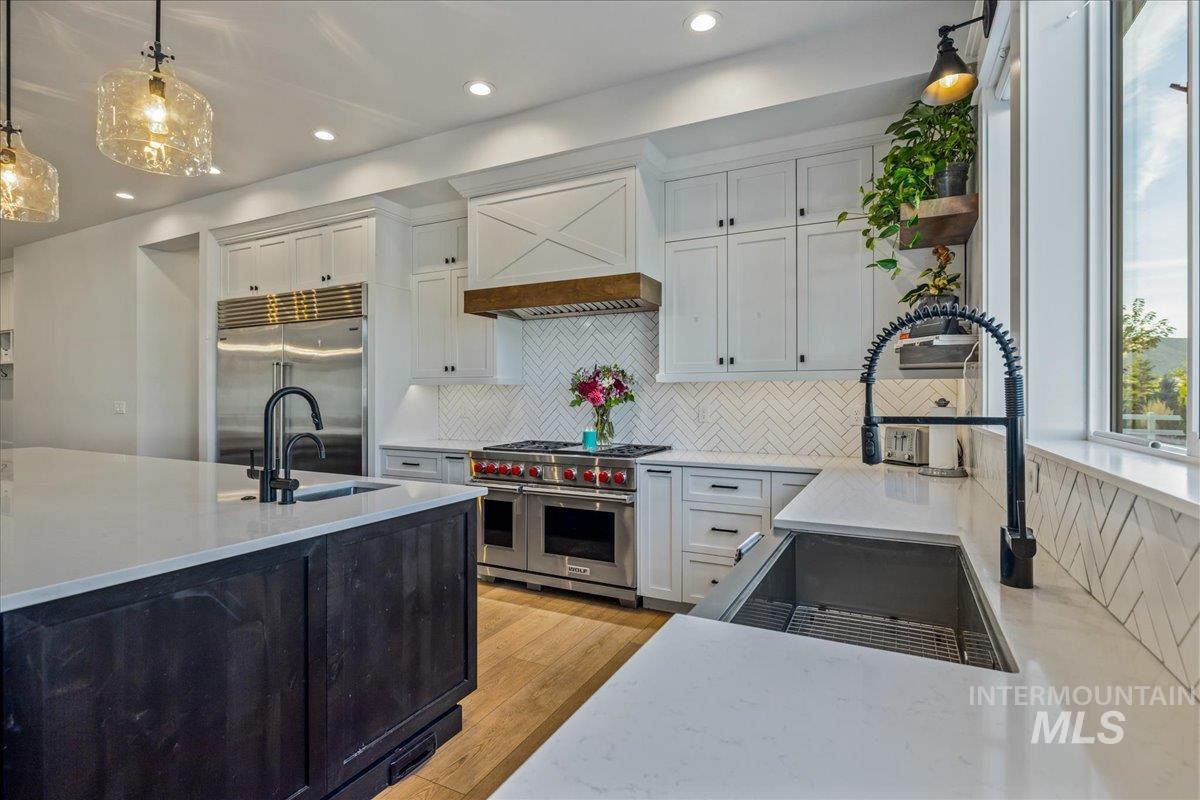 Kitchen featuring pendant lighting, white cabinetry, backsplash, light stone countertops, and recessed lighting