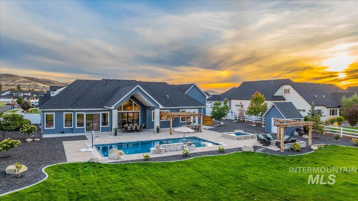 Back of property at dusk with a patio, a fenced backyard, a pergola, and an in-ground hot tub
