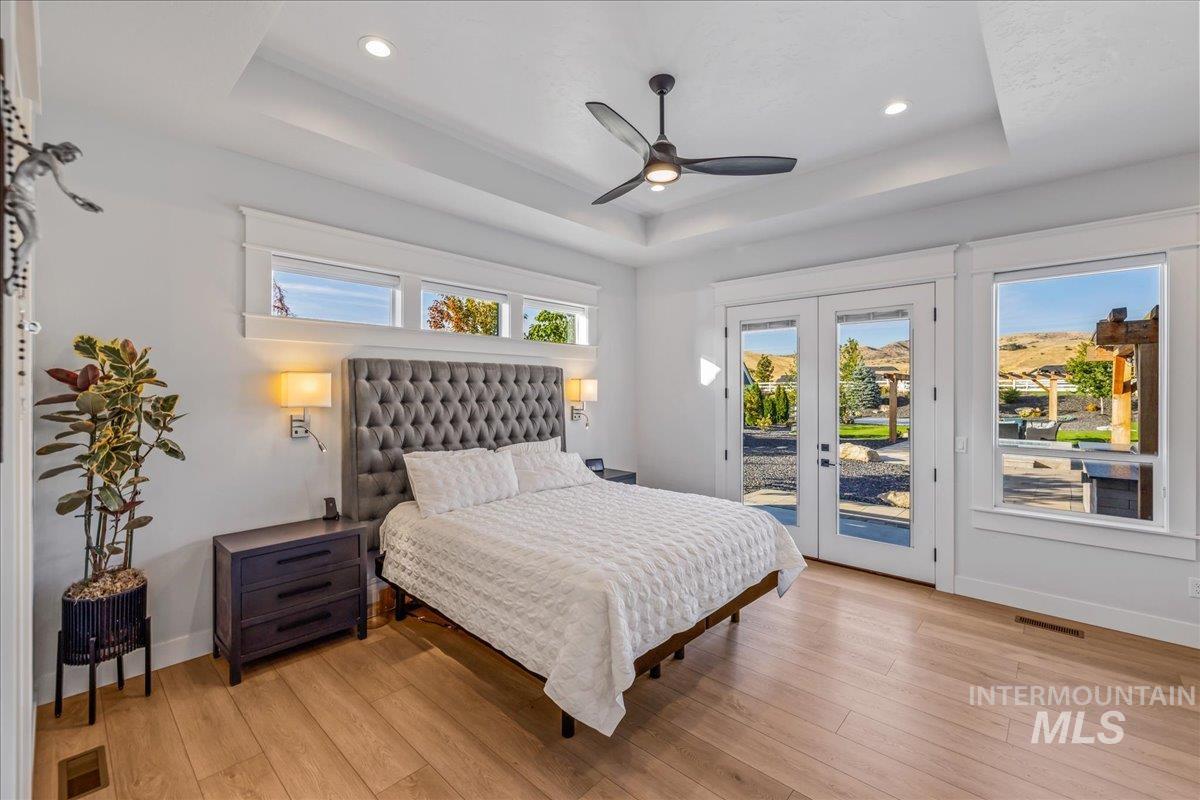 Bedroom with a raised ceiling, multiple windows, access to outside, and recessed lighting