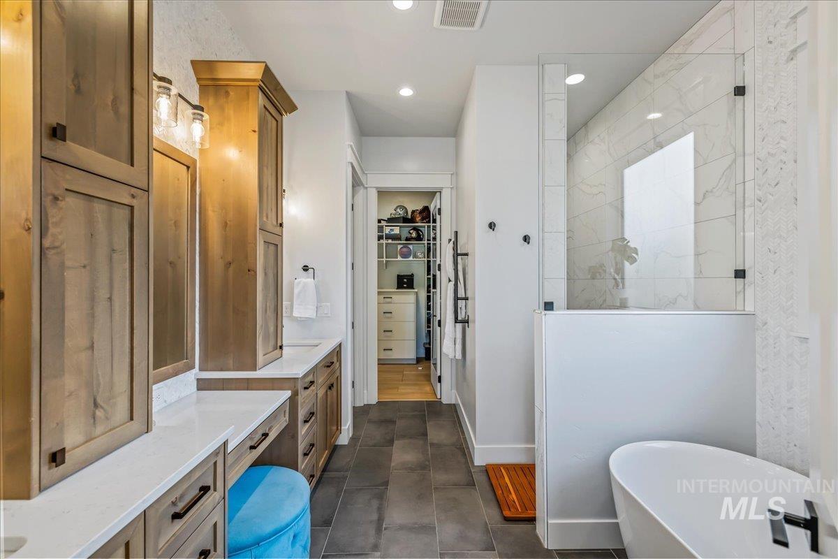 Full bath featuring walk in shower, a spacious closet, vanity, a soaking tub, and recessed lighting
