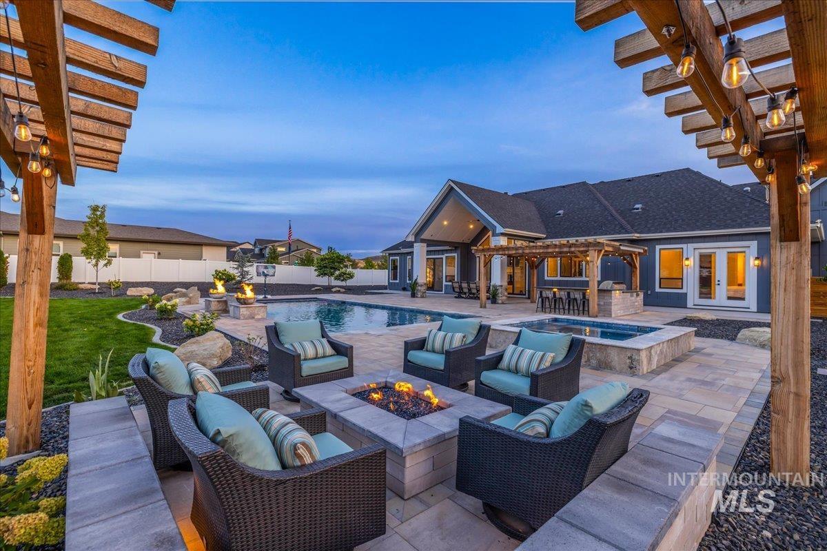 Pool at dusk featuring a pergola, a patio area, a pool with connected hot tub, and an outdoor living space with a fire pit