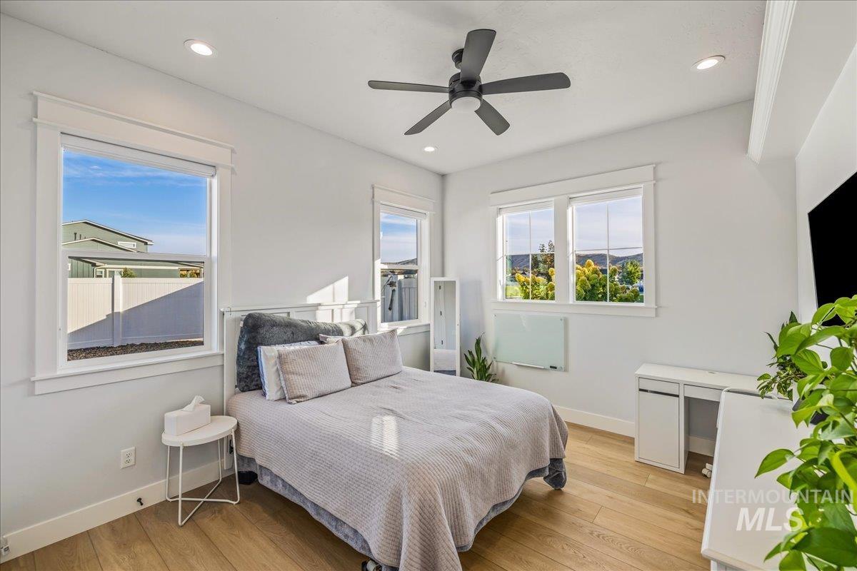 Bedroom with light wood finished floors, ceiling fan, and recessed lighting