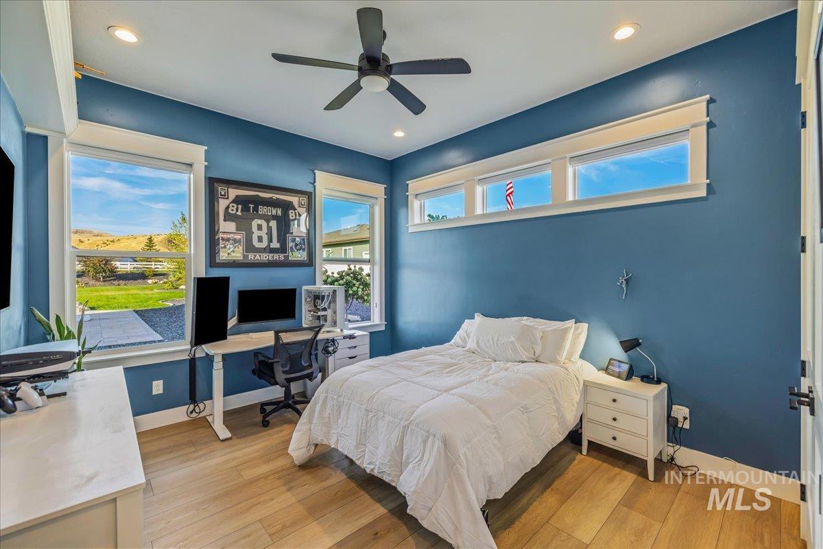 Bedroom with a desk, light wood finished floors, multiple windows, a ceiling fan, and recessed lighting