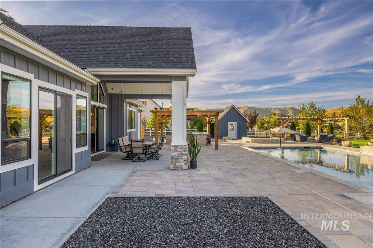 View of patio featuring an outdoor pool, a mountain view, a pergola, outdoor dining area, and an outbuilding