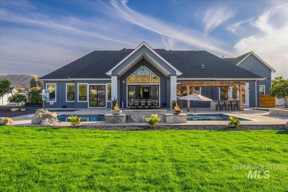 Back of property featuring an outdoor pool, board and batten siding, a patio, and a shingled roof