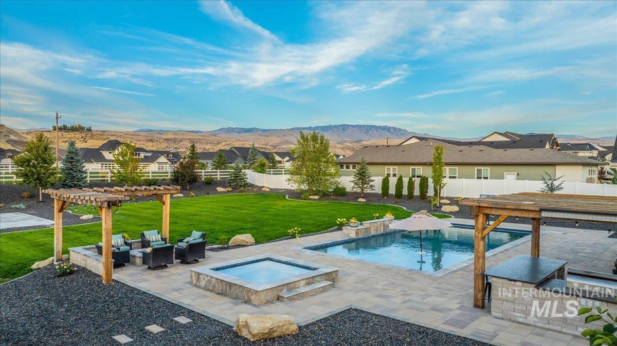 View of swimming pool featuring a patio, a pergola, a fenced backyard, an in-ground hot tub, and a residential view