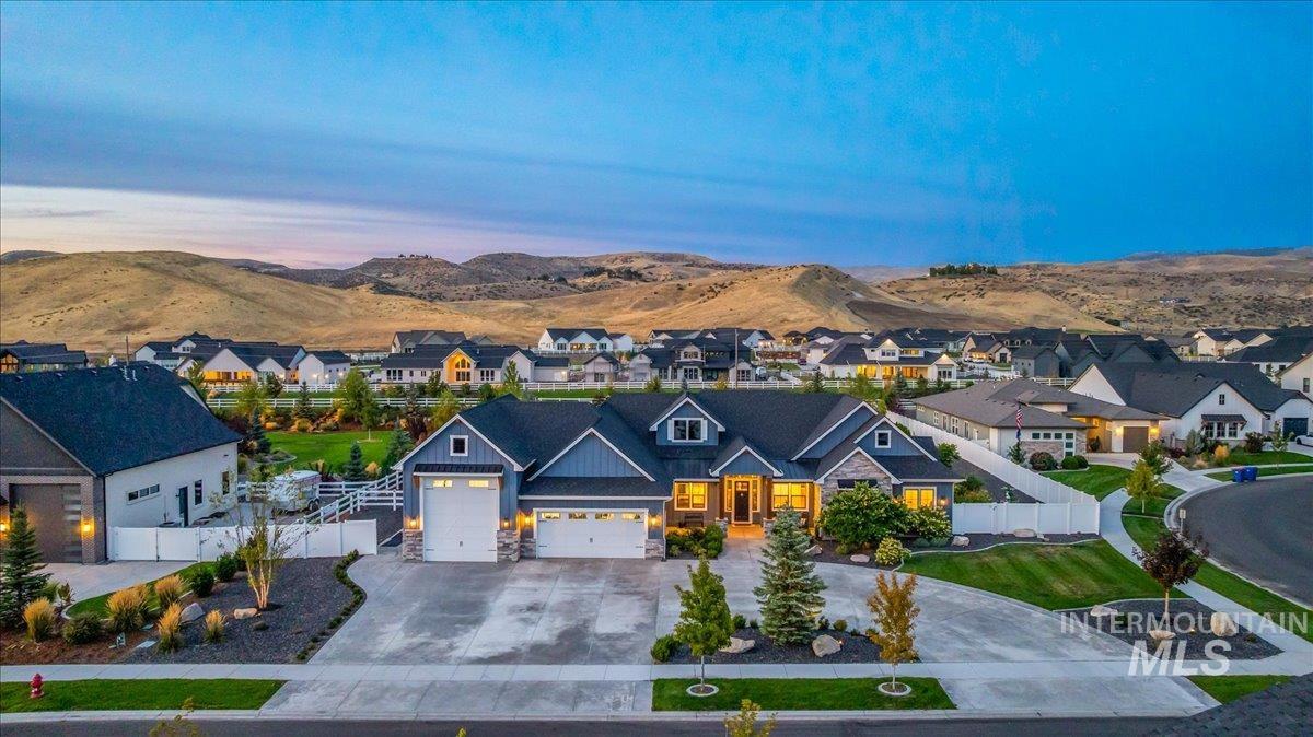 View of front of house with driveway, stone siding, a mountain view, and an attached garage