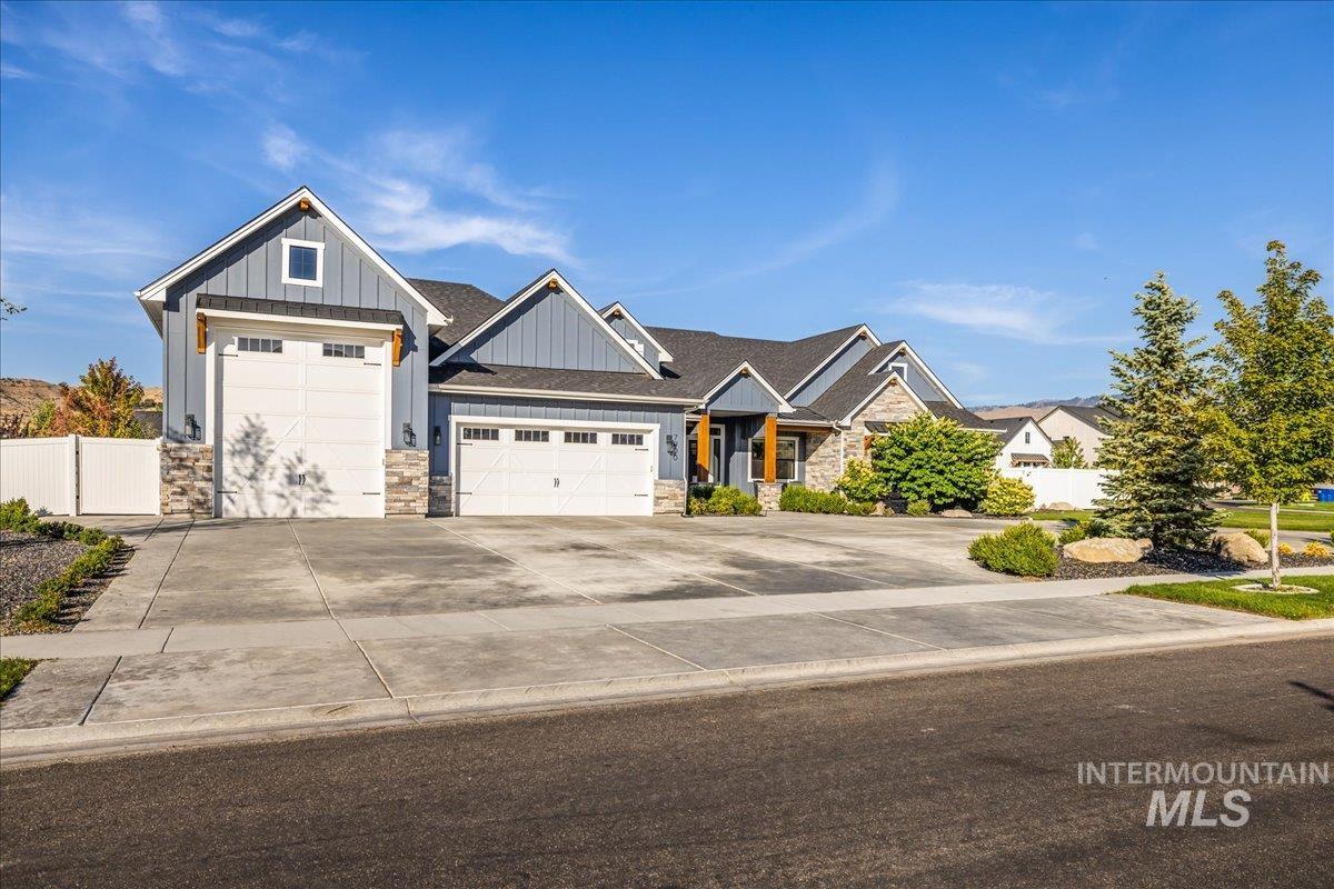 Craftsman house with board and batten siding, stone siding, a garage, and concrete driveway