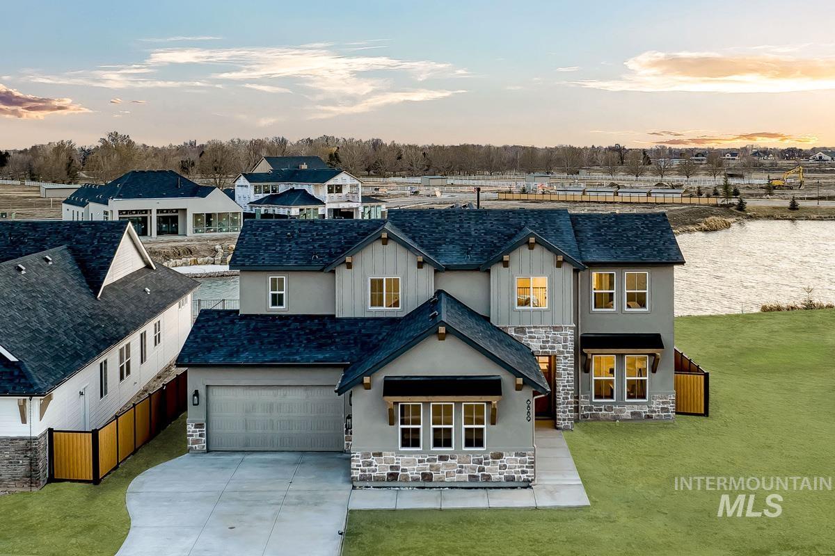 View of front of property featuring stone siding, driveway, a garage, and board and batten siding