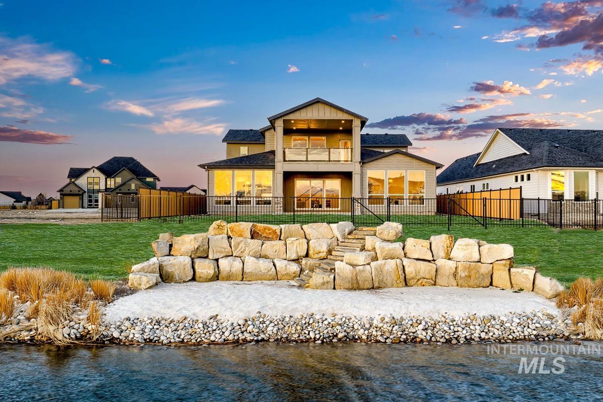 Back of property featuring a balcony, a patio, a water view, and a yard
