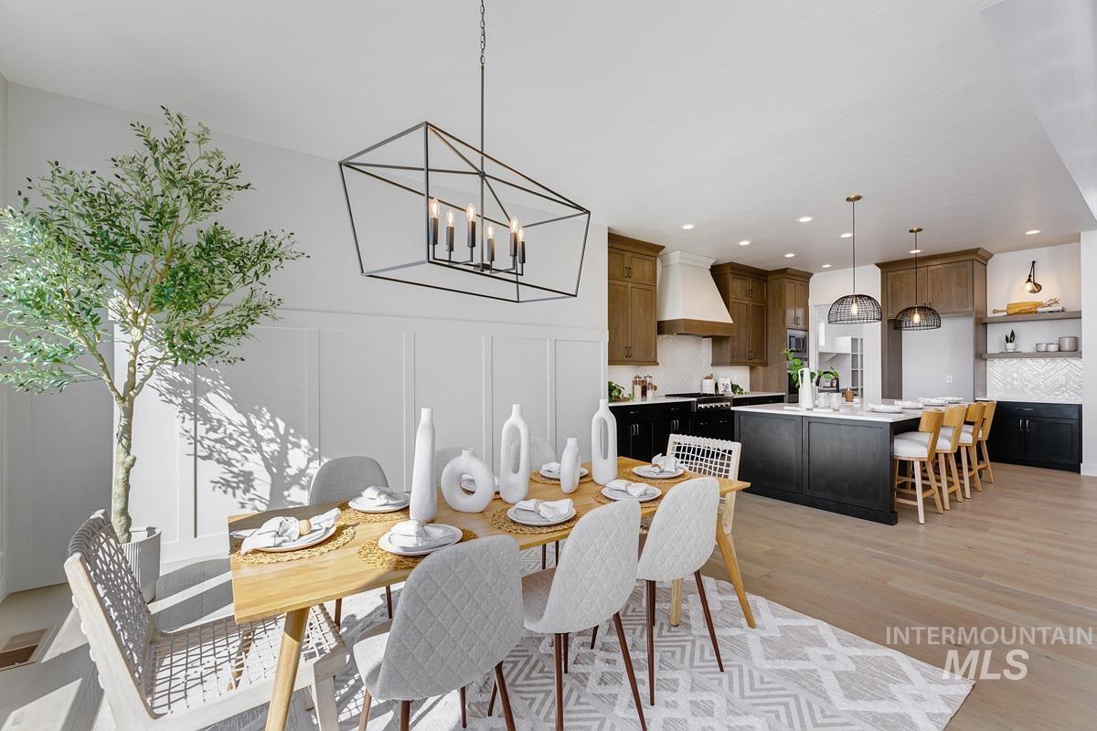 Dining room featuring a decorative wall, light wood-type flooring, a chandelier, and recessed lighting