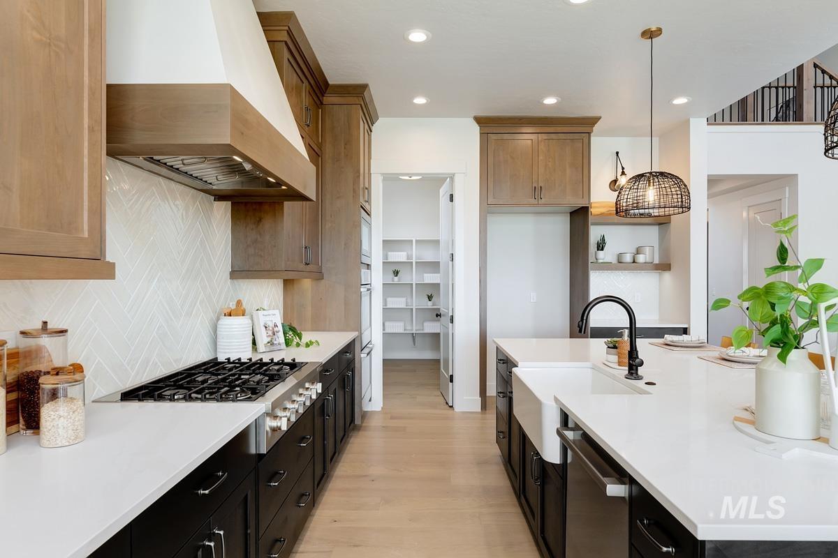 Kitchen featuring stainless steel appliances, custom range hood, hanging light fixtures, recessed lighting, and light wood finished floors