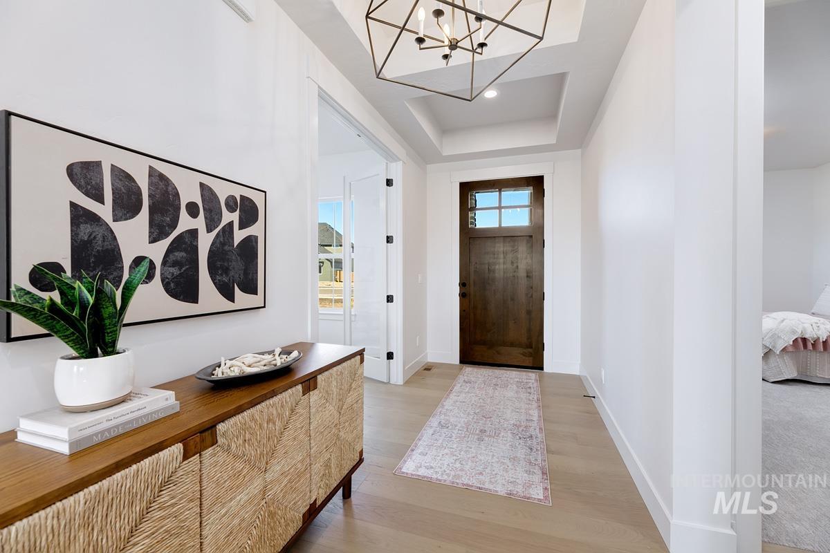 Foyer with a chandelier, light wood-style floors, and a raised ceiling