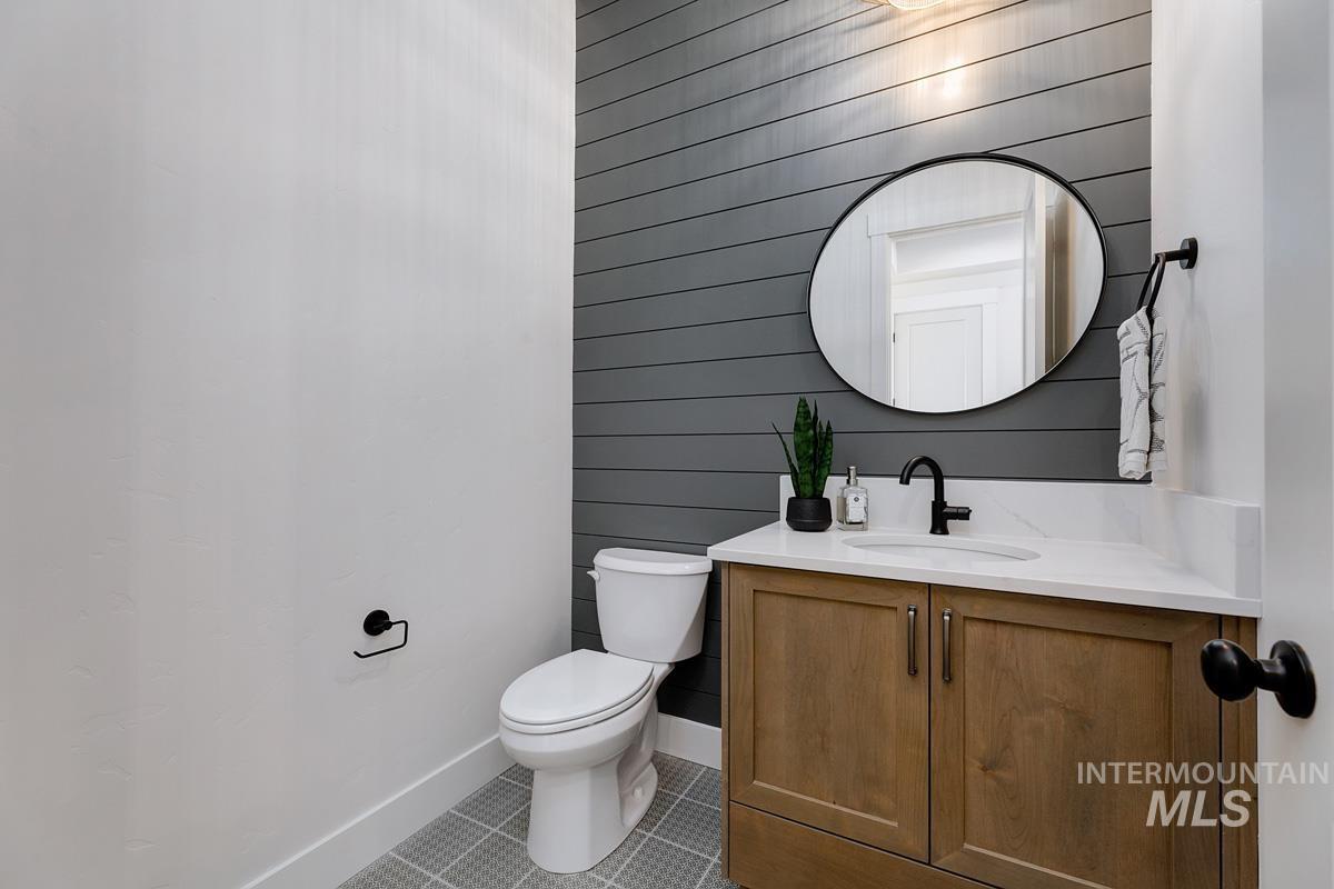Half bath featuring vanity, light tile patterned floors, and wooden walls