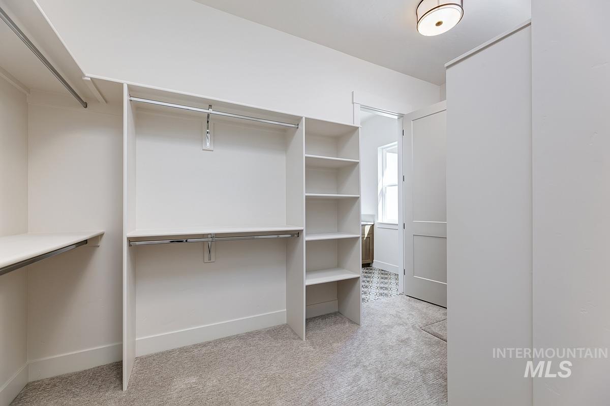 Spacious closet featuring light colored carpet
