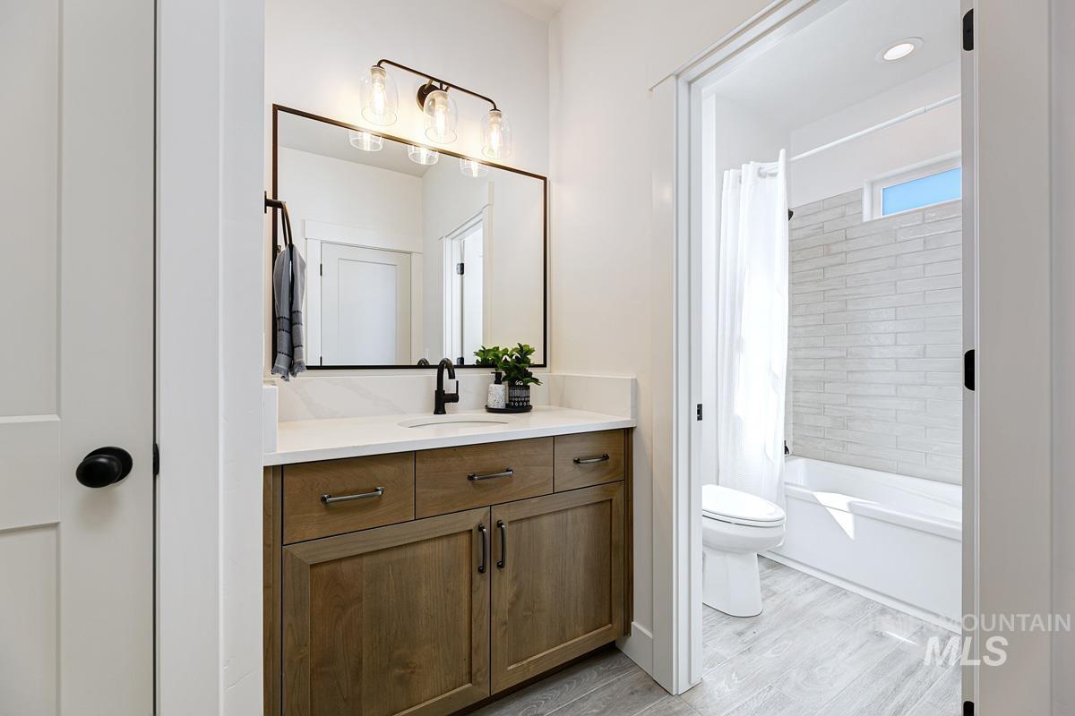Bathroom featuring vanity, shower / bath combo, and light wood finished floors
