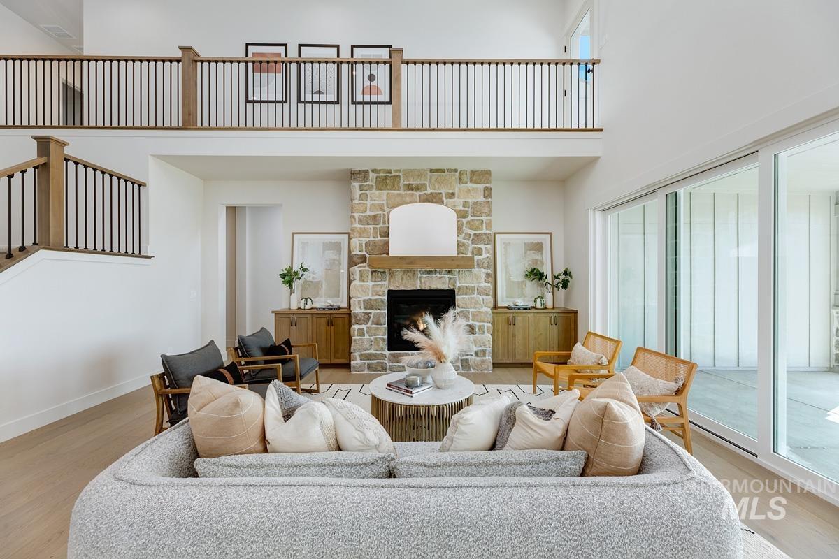 Living room with a high ceiling, wood finished floors, and a fireplace