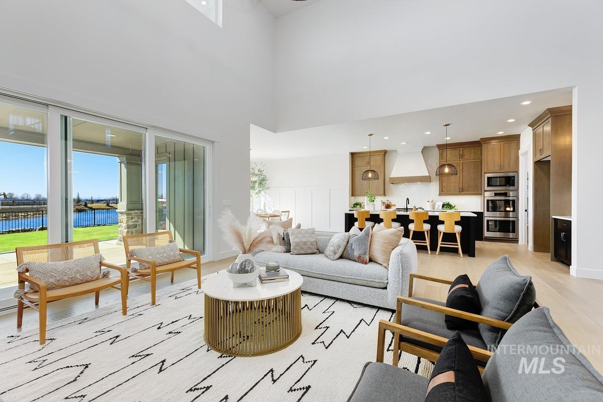 Living area with healthy amount of natural light, a water view, a high ceiling, recessed lighting, and light wood-type flooring