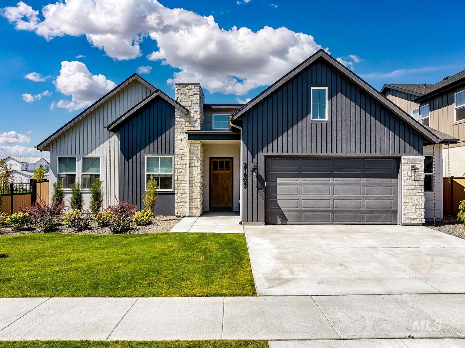 Modern farmhouse with board and batten siding, stone siding, driveway, and a garage