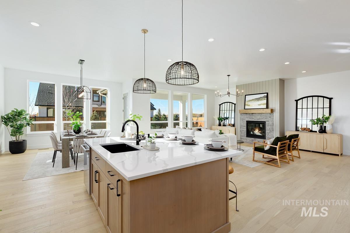 Kitchen with light wood-style floors, hanging light fixtures, recessed lighting, light stone countertops, and a kitchen breakfast bar