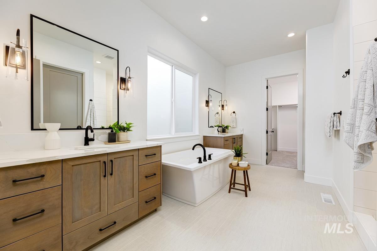Bathroom featuring vanity, a freestanding tub, a walk in closet, and recessed lighting