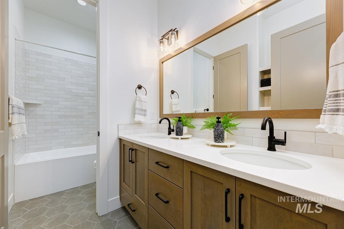 Bathroom featuring double vanity, light tile patterned floors, and shower / bath combo