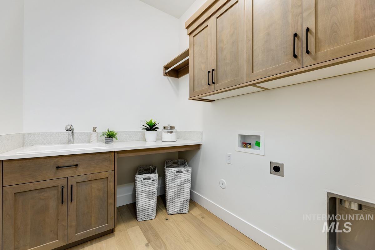Laundry room featuring hookup for a washing machine, light wood-style flooring, cabinet space, and hookup for an electric dryer