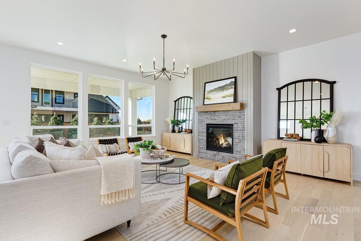Living room featuring recessed lighting, a brick fireplace, light wood-style floors, and a chandelier