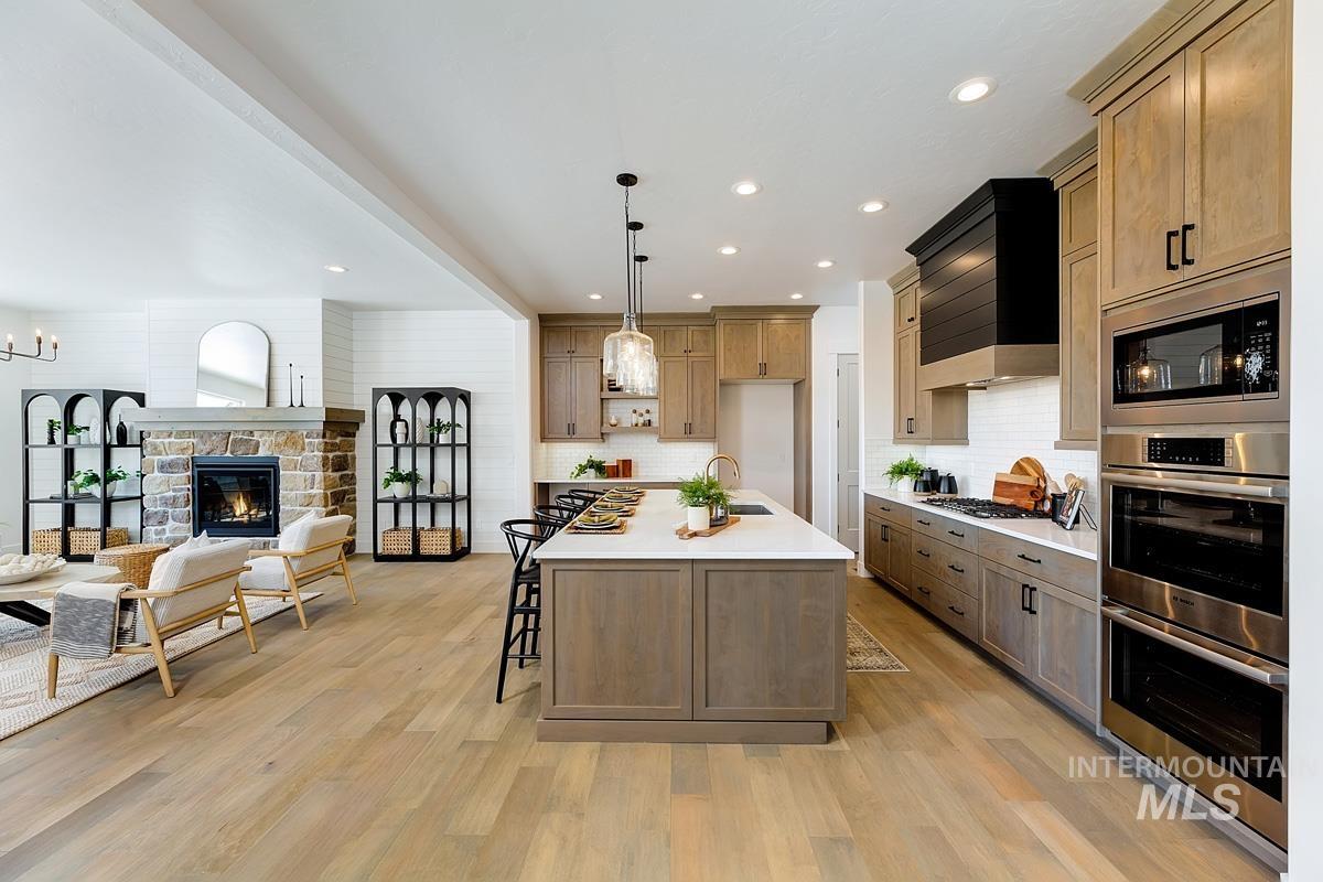Kitchen with decorative light fixtures, appliances with stainless steel finishes, open floor plan, recessed lighting, and a kitchen bar